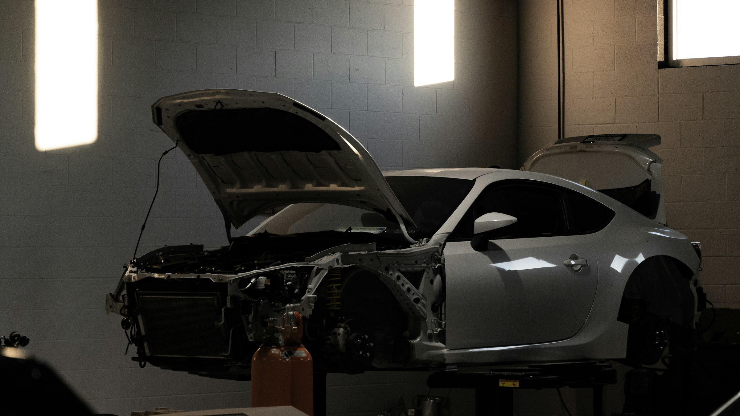 A car on stands in a workshop, bonnet open